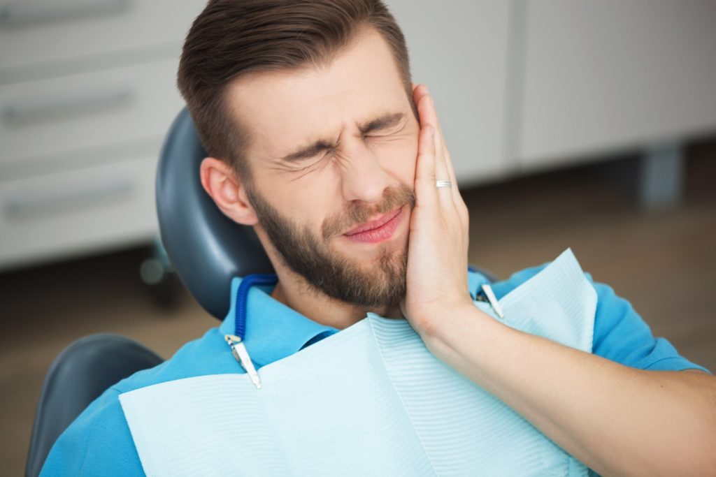 Young man with tooth pain sitting in a dentist's chair.